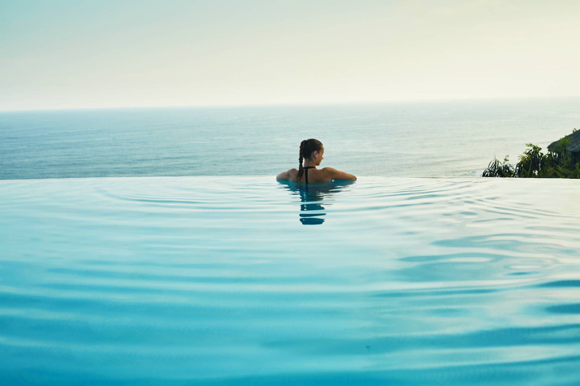 luxury-resort-pool-sea-woman-shutterstock_436157680
