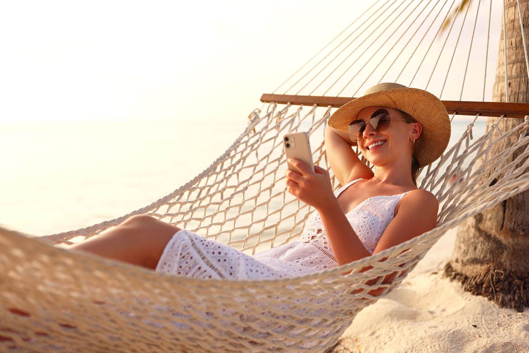 Young happy woman, female freelancer in straw hat and sunglasses working on smartphone © Shutterstock