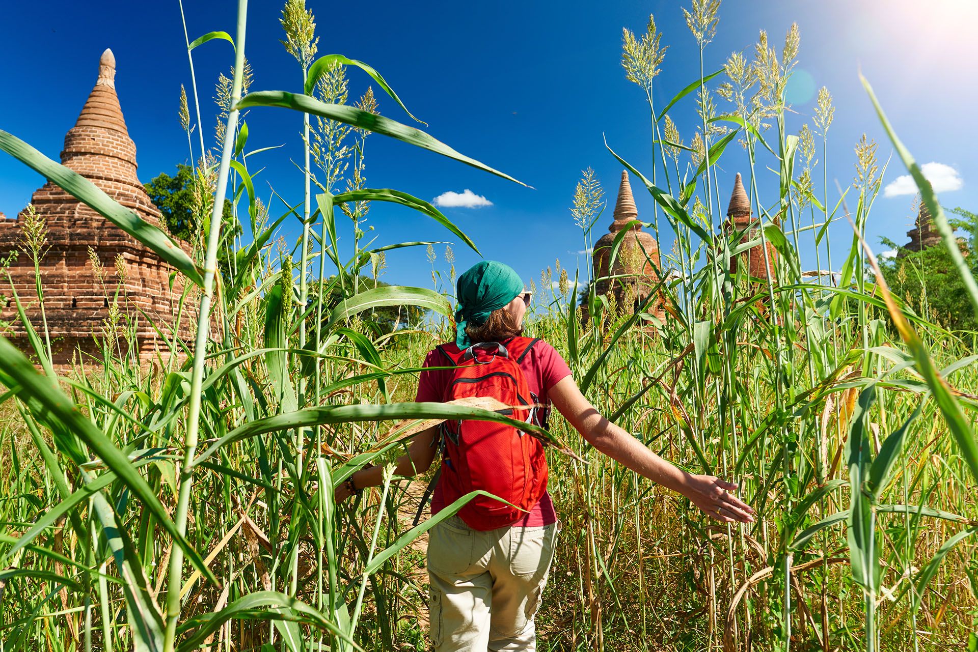 Rear view of young woman traveler with a backpack walking through the field to the ancient Buddhist stupas, Myanmar © soft_light/Shutterstock